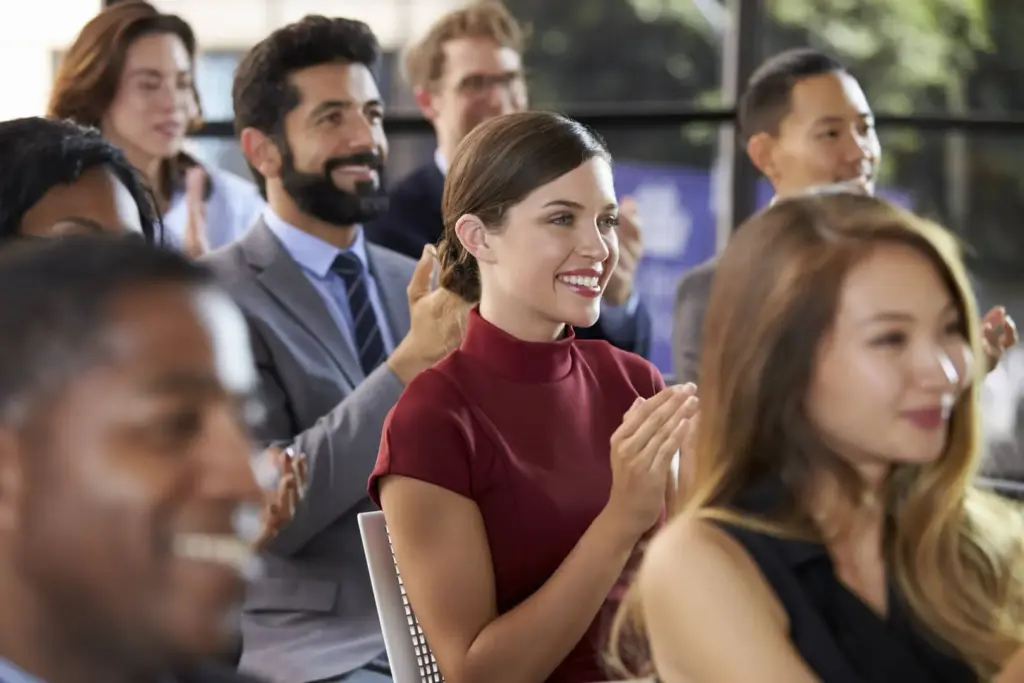 Persone applaudono durante una conferenza o presentazione pubblica.